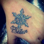 Фото тату: красивая снежинка с голубыми и белыми оттенками и надписью 'Believe' на запястье. Изящный рисунок татуировки для девушек.