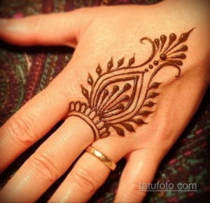 Фото тату хной на ладони, изображающее элегантный рисунок в форме пера с использованием коричневых оттенков.
