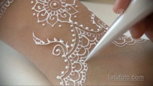 Фото процесса нанесения татуировки хной на кожу, демонстрирующее работу мастера и тонкость узора. Идеально для понимания техники мехенди.