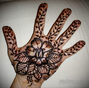 Фото тату мехенди на ладони, с крупным цветочным узором в центре и мелкими деталями, тянущимися к пальцам. Идеально для тех, кто любит сложные и детализированные рисунки.