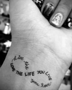 Фото тату: Надпись "Live the life you love" в виде браслета на запястье. Мотивационная татуировка с красивым шрифтом.