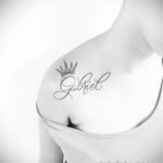 Фото тату с именем 'Gabriel' и короной на плече. Черно-белая татуировка, выполненная в каллиграфическом стиле с добавлением изображения короны.