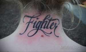 Фото тату с надписью 'Fighter' на шее. Черный контур, каллиграфический шрифт, динамичный дизайн. Татуировка для тех, кто не сдается.