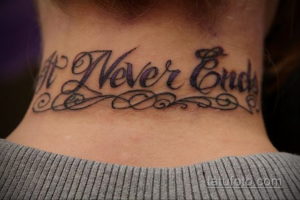 Фото тату с надписью 'It Never Ends' на шее. Черно-фиолетовые чернила, каллиграфический шрифт, декоративные завитки. Стильная и дерзкая татуировка для смелых личностей.