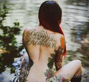 Фото тату с надписью 'Beauty in the Breakdown' на спине. Каллиграфия, яркие цвета, цветочные элементы. Идеи для тату на спине.