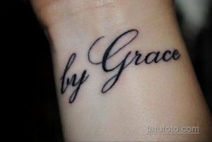 Фото тату с надписью "by Grace", выполненной элегантным каллиграфическим шрифтом на женском запястье.