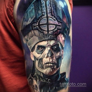 Фото татуировки на плече с изображением Papa Emeritus из группы Ghost в жутком и реалистичном стиле.