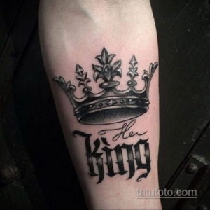 Фото тату короны и надписи "Her King" на предплечье. Черно-белый рисунок с использованием каллиграфического шрифта. Романтичный дизайн.