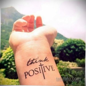 Фото тату на запястье, изображающее надпись "Think Positive" с крестом вместо буквы "T". Простой и вдохновляющий рисунок татуировки.