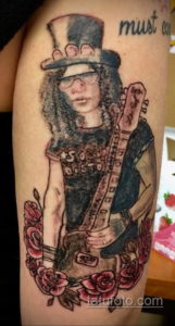 Фото тату портрета Слэша, гитариста Guns N' Roses, с гитарой и розами на руке. Реалистичный рисунок в цвете.