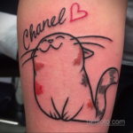 Фото тату кота с надписью 'Chanel' на руке. Забавный рисунок в минималистичном стиле, выполненный в черном и красном цветах.
