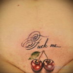 Фото тату с надписью 'Fuck me' и изображением двух спелых вишен. Рисунок выполнен в черном цвете с реалистичными деталями.