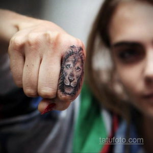 Фото тату реалистичной головы волка на костяшке пальца. Детализированный рисунок татуировки в черно-серых тонах.