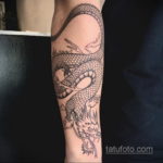 Фото тату черного дракона на мужской руке в стиле line work. Рисунок выполнен тонкими линиями, создающими эффект гравировки.
