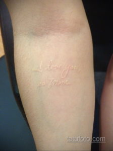 Фото белой татуировки на руке с надписью 'I love you, Mom'. Нежный шрифт, минималистичный дизайн.