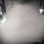 Фото тату белого цветка лотоса на шее. Изящный рисунок, выполненный в технике white ink, символизирует чистоту и духовность.