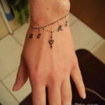 Фото тату: браслет из точек с инициалами и маленьким сердцем на запястье. Персонализированный и романтичный дизайн.