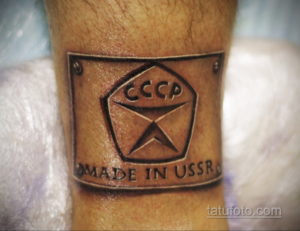 Фото тату на руке с изображением советского герба и надписью 'Made in USSR', выполненное в классическом стиле с использованием черных чернил.