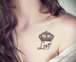 Фото тату маленькой черной короны с надписью 'Love' на ключице девушки. Эскиз татуировки выполнен в минималистичном стиле, с четкими линиями.