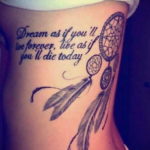 Фото тату на боку с изображением ловца снов и надписью "Dream as if you'll live forever, live as if you'll die today". Черно-белый рисунок татуировки с детализированной проработкой.