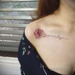 Фото тату на плече с изображением розового цветка и надписью 'Lovingly'. Акварельный стиль, нежные пастельные тона.