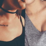 Фото тату на ключицах с надписями 'Love her, but leave her wild' и 'Faith is worth me'. Тонкие черные линии, женственный стиль.