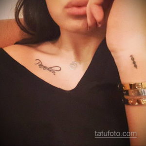 Фото тату с именем "Paola" на ключице и небольшим символом на руке. Черно-белый рисунок татуировки каллиграфическим шрифтом.