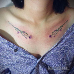 Фото тату: изящные лиловые цветы с зелеными стеблями, расположенные вдоль ключицы, создают женственный и утонченный образ.