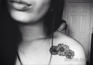 Фото тату: четыре ромашки, выполненные в технике blackwork, расположены на плече. Минималистичный и элегантный рисунок татуировки.