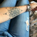 Фото тату: большая татуировка в стиле кружева на руке, имитирующая вязаный узор. Черно-белый рисунок с детальной проработкой.