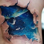 Фото 3D тату на боку, имитирующее прорыв в космос. Реалистичный рисунок татуировки с изображением звездного неба и планеты.