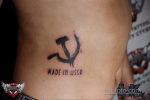Фото татуировки с изображением серпа и молота и надписи 'Made in USSR' на боку. Простой и лаконичный рисунок татуировки.