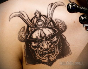 Фото тату самурайской маски на груди. Рисунок выполнен в технике blackwork с использованием четких линий и контрастных теней. Эскиз татуировки.