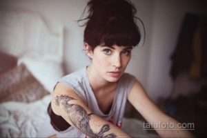 Фото тату павлина на руке девушки, выполненное в технике графики с использованием черных чернил. Детализированный рисунок татуировки.