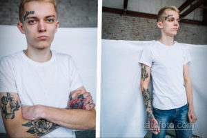 Фото тату на мужчине: надпись 'Loneliness' на лбу и татуировки на руках с изображением скальпа и цветов. Рисунок татуировки.