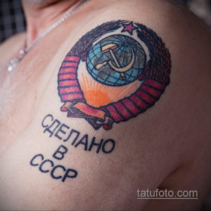 Фото тату на груди: знак качества "Сделано в СССР" с изображением земного шара, серпа и молота. Винтажный рисунок татуировки в ярких цветах.