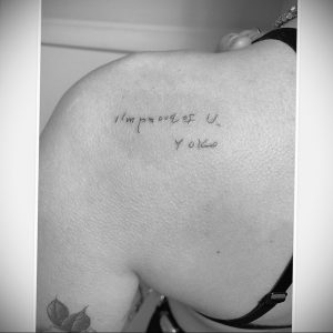 Фото тату: минималистичная татуировка на плече с надписью "I'm proud of U Yoko" выполненная тонким черным контуром.