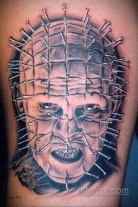 Черно-серое фото татуировки Пинхеда, персонажа из фильма Hellraiser, на руке. Детализированный рисунок с множеством булавок в голове.