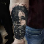 Фото тату с изображением портрета девушки, часть лица которой переходит в лестничный пролет, выполнено в черно-серых тонах с высокой детализацией.