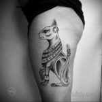 Фото тату богини Бастет на бедре, выполненное в стиле blackwork с использованием черных линий и узоров. Изображение детализированное, с проработкой украшений и одежды.