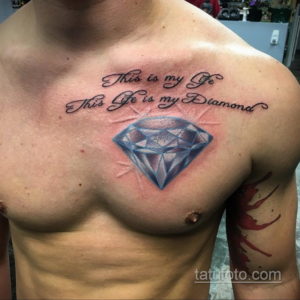 Фото татуировки бриллианта на груди с надписью "This is my Life This Life is my Diamond". Реалистичный стиль, голубые оттенки, каллиграфический шрифт.