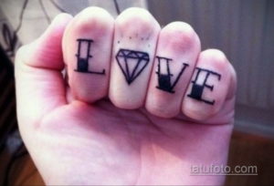 Фото тату: надпись "LOVE" с бриллиантом вместо буквы "O" на пальцах руки. Женская татуировка, оригинальный дизайн.