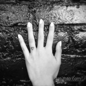 Фото тату маленького черного бриллианта на пальце руки. Простой и элегантный рисунок татуировки, выполненный в минималистичном стиле.