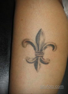 Фото тату флёр-де-лис в черно-серых тонах на руке. Минималистичный рисунок с четкими контурами и лаконичным дизайном.