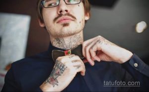 Фото тату на шее и руке мужчины, выполненное в темных тонах с использованием геометрических узоров и символов. Детализированная татуировка выглядит эффектно.