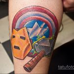 Фото тату: щит Капитана Америки и молот Тора. Яркий рисунок с элементами комиксов и супергероев. Татуировка на предплечье.