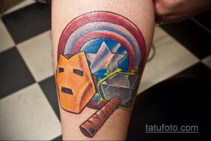 Фото тату: щит Капитана Америки и молот Тора. Яркий рисунок с элементами комиксов и супергероев. Татуировка на предплечье.