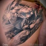 Фото тату Космического Сёрфера на спине, выполненное в реалистичном стиле с использованием черных и серых оттенков и космических элементов.
