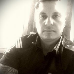 Фото полицейского в форме с татуировкой на руке. Детализированный рисунок татуировки в классическом стиле.
