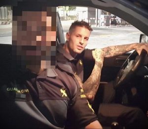 Фото полицейского за рулем автомобиля с татуировкой на руке. Детализированный рисунок татуировки в темных тонах.